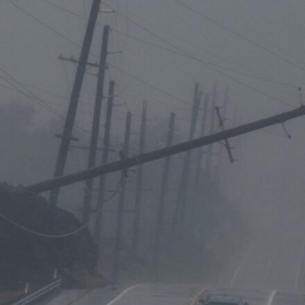 A vehicle drives near a downed utility pole dangling above Mamalahoa Highway during Hurricane Lala near Ocean View, Hawaii. (Stephen Lam/San Francisco Chroni)